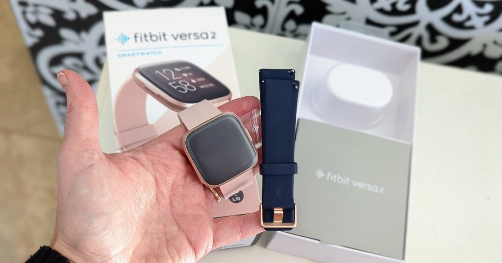 hand holding pink fitbit watch with open box