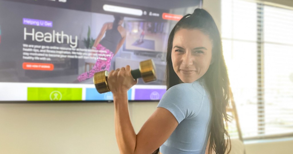 woman holding a dumbbell in front of a TV