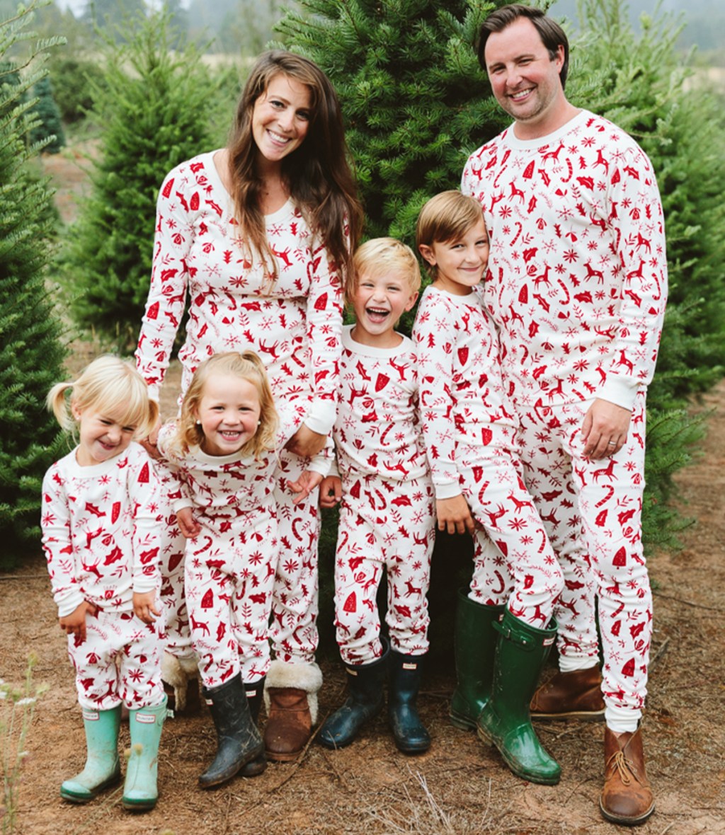 family standing outside in front of evergreen trees wearing best matching family pajamas