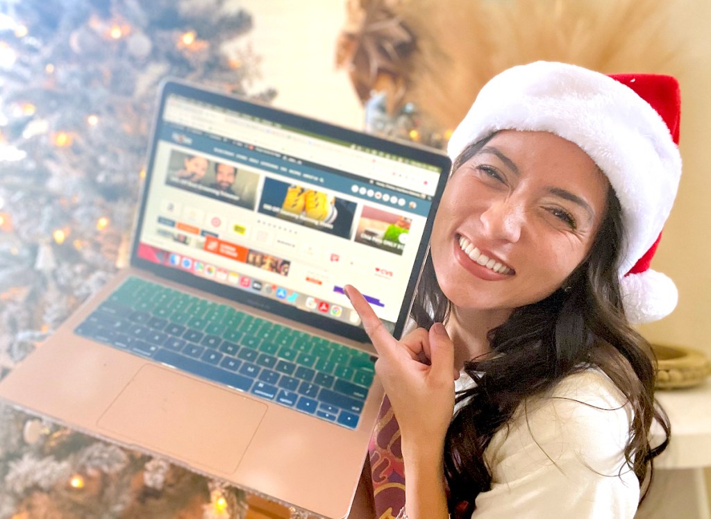 woman holding up laptop and wearing santa hat