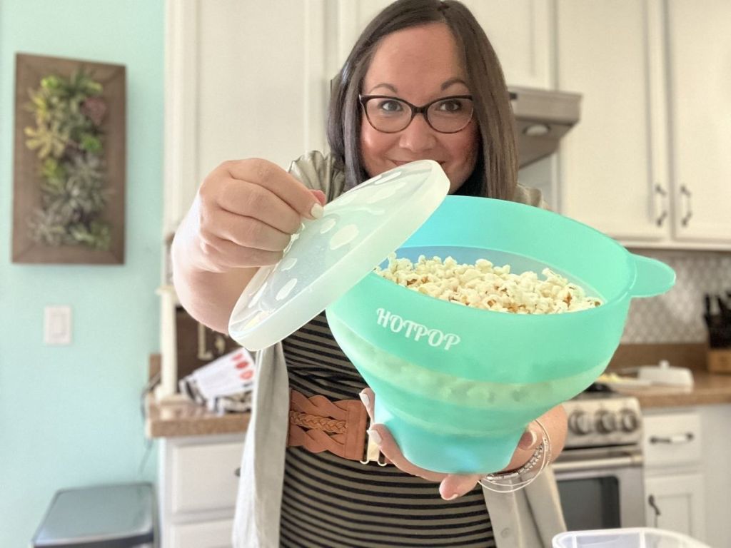 woman lifting lid off silicone popcorn bowl