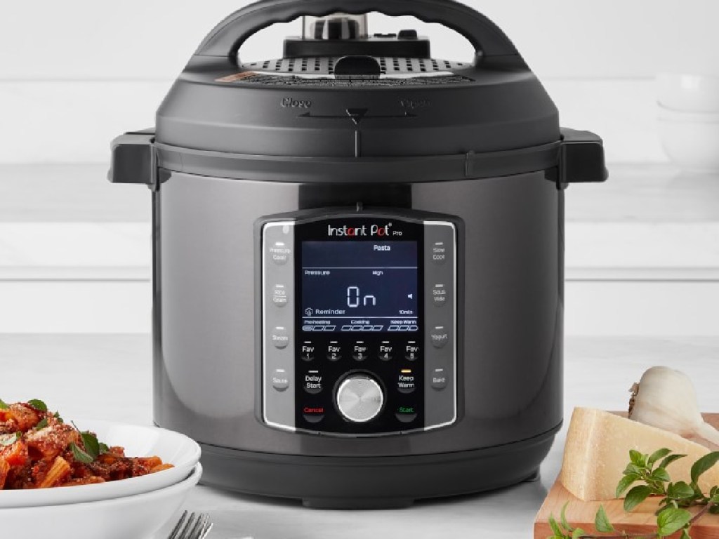 black colored kitchen Instant pot with bowls of food next to it