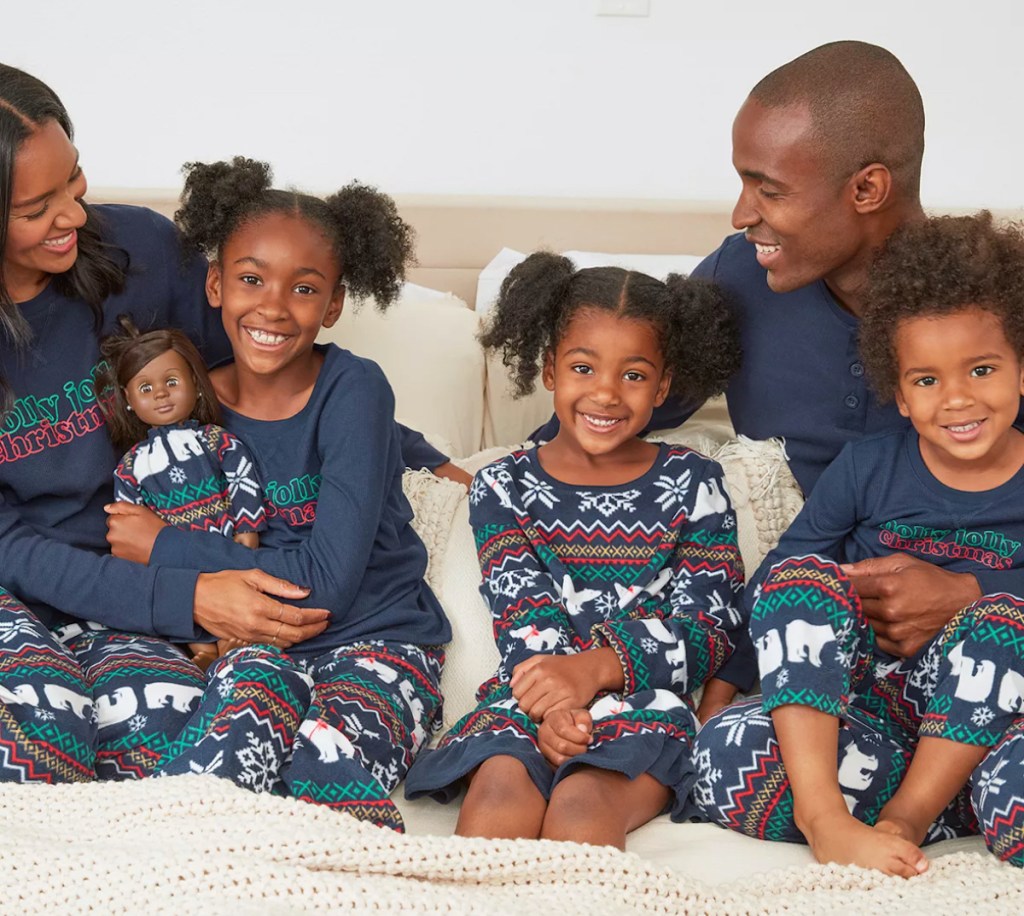 family of five sitting on bed wearing matching family christmas jammies