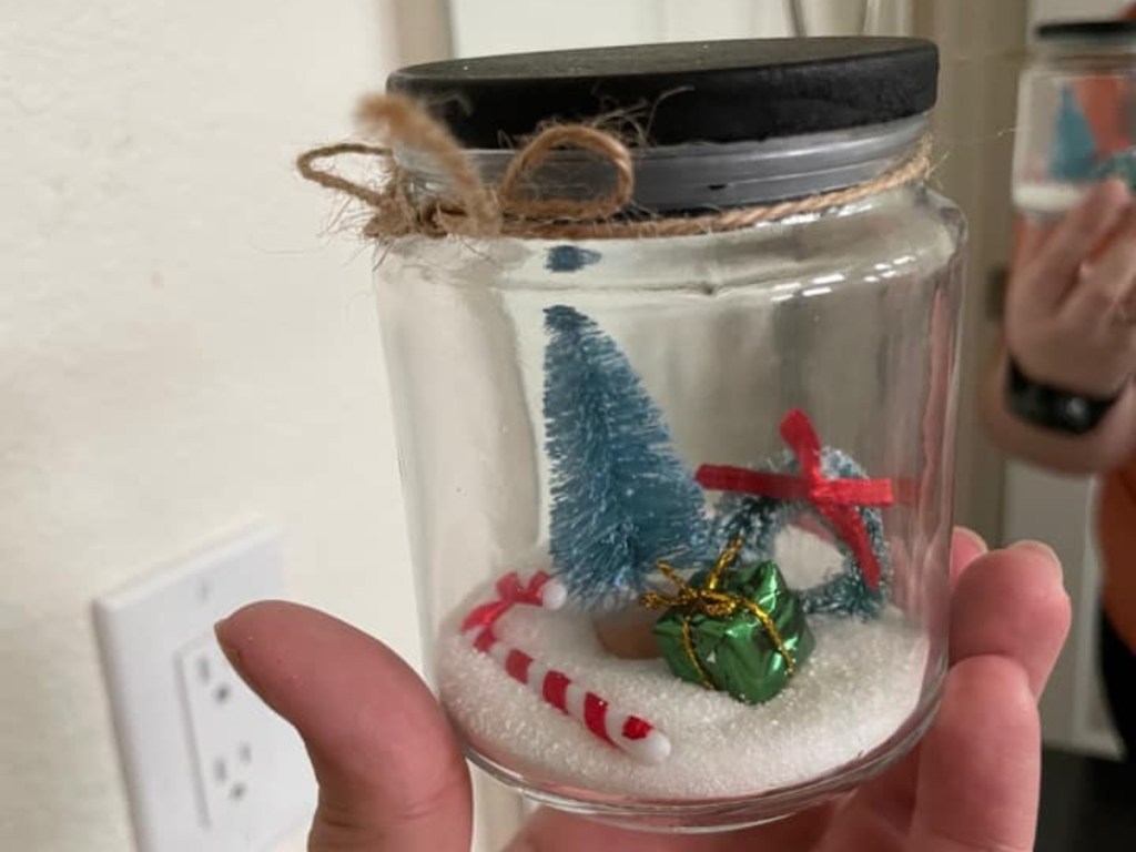 holding a homemade snowglobe in a jar