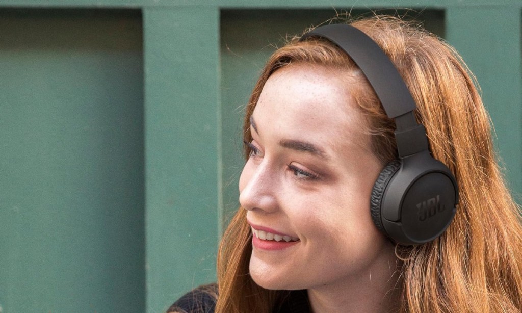 smiling woman wearing jbl on ear headphones