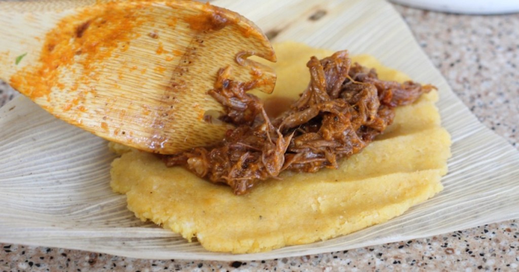 wooden spoon putting beef on tamales