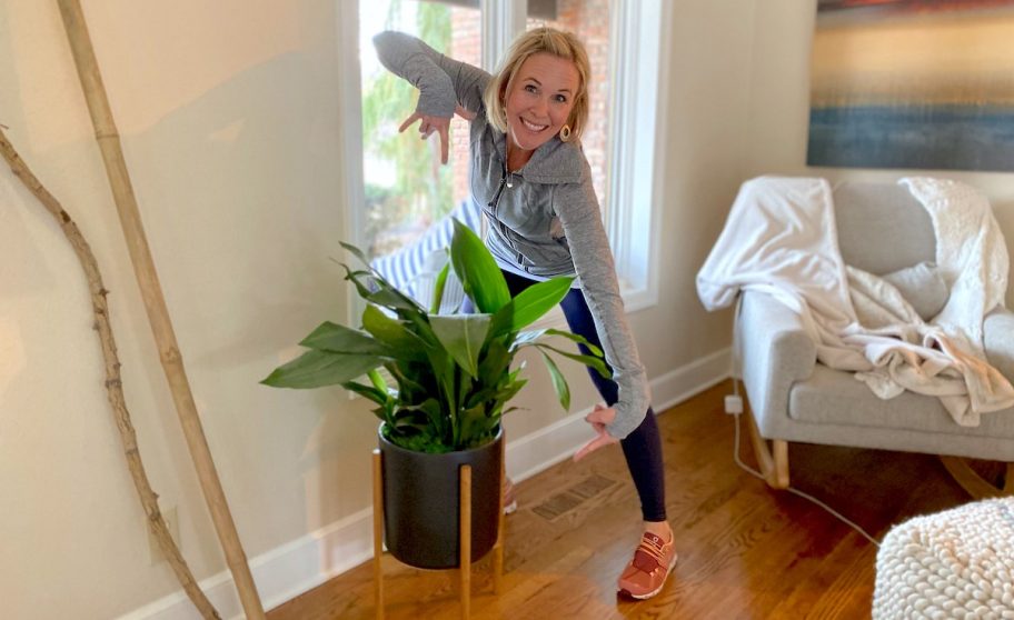 woman hovering over and pointing to plant in black planter