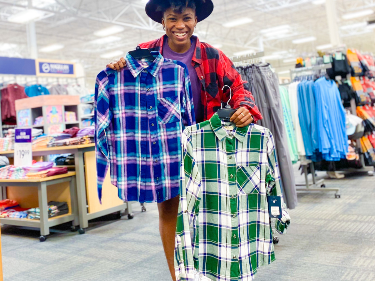 woman holding two plaid shirts inside store