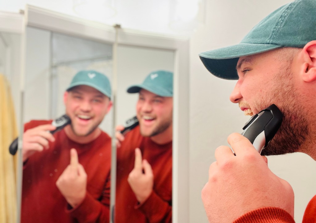 man using suprent beard trimmer in mirror
