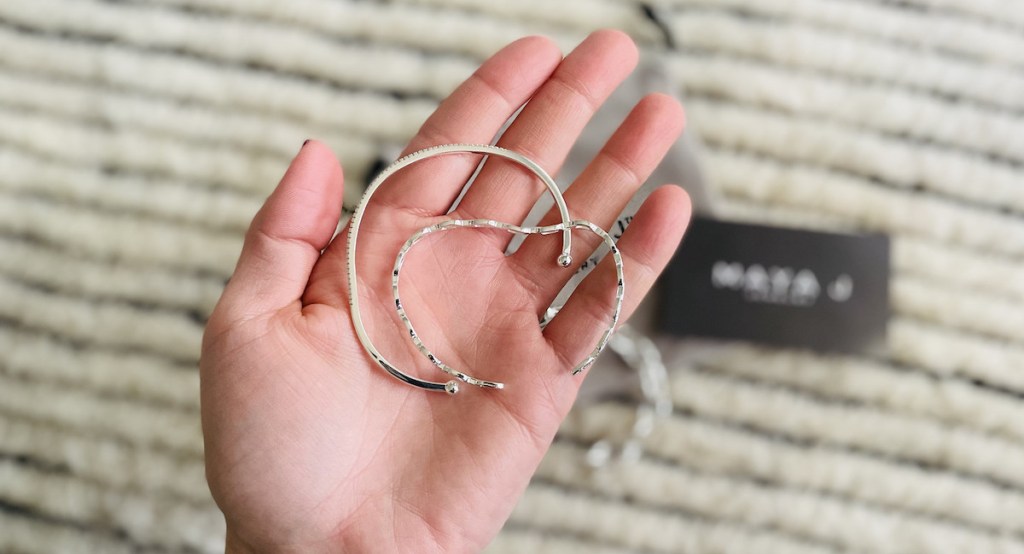 hand holding two silver bent up bracelets in palm - oprah's favorite things