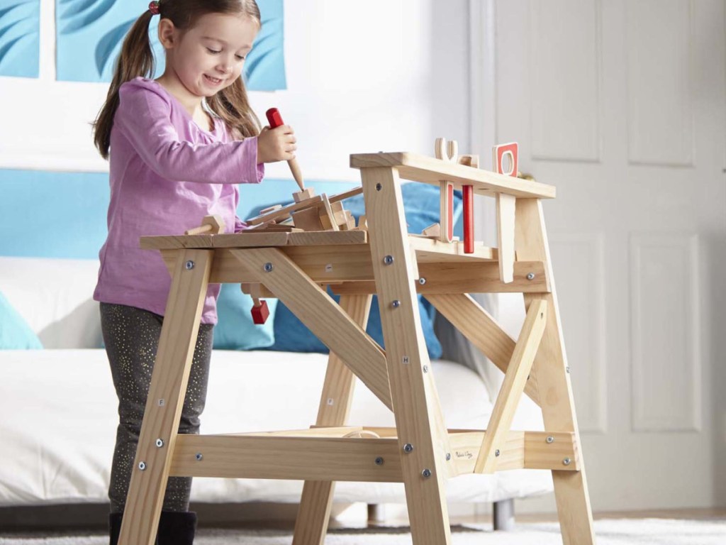girl playing on a small wooden workbench for kids