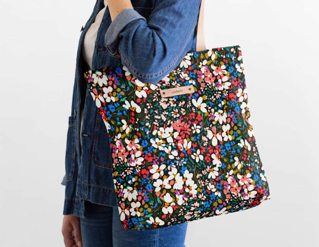 woman holding canvas tote bag with flowers over shoulder