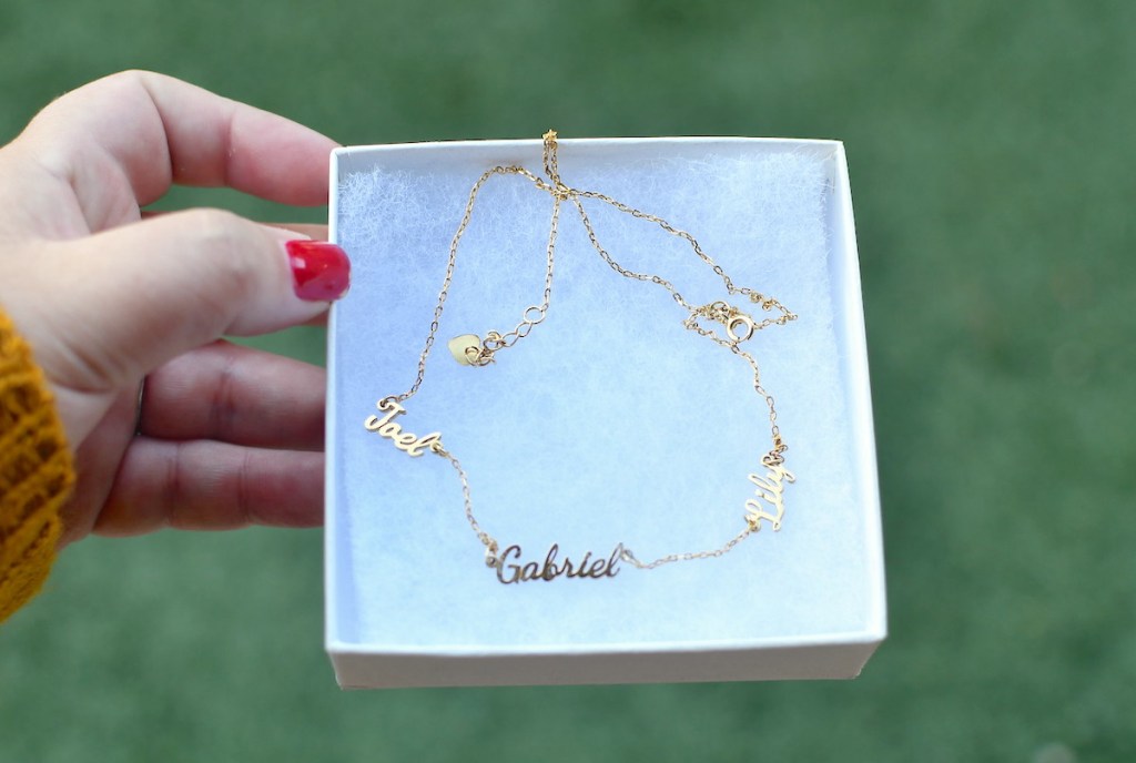 hand holding a white jewelry box with name necklace inside