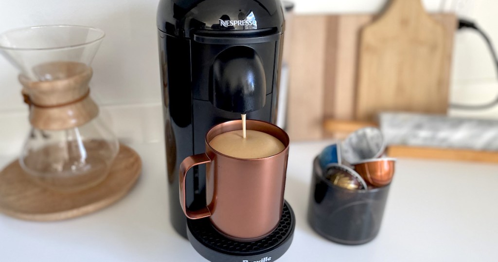 nespresso coffee maker with copper mug pouring coffee