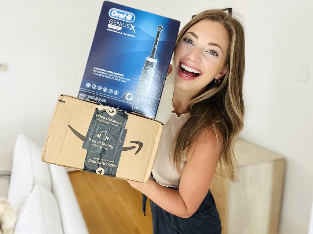 woman holding oral b and amazon boxes smiling