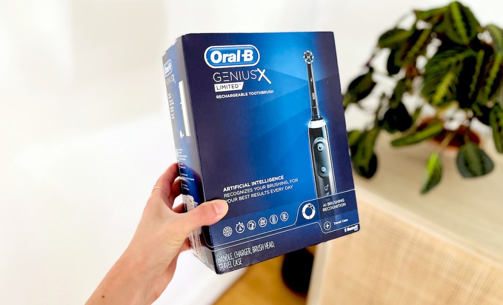 hand holding an oral b genius x limited toothbrush box 