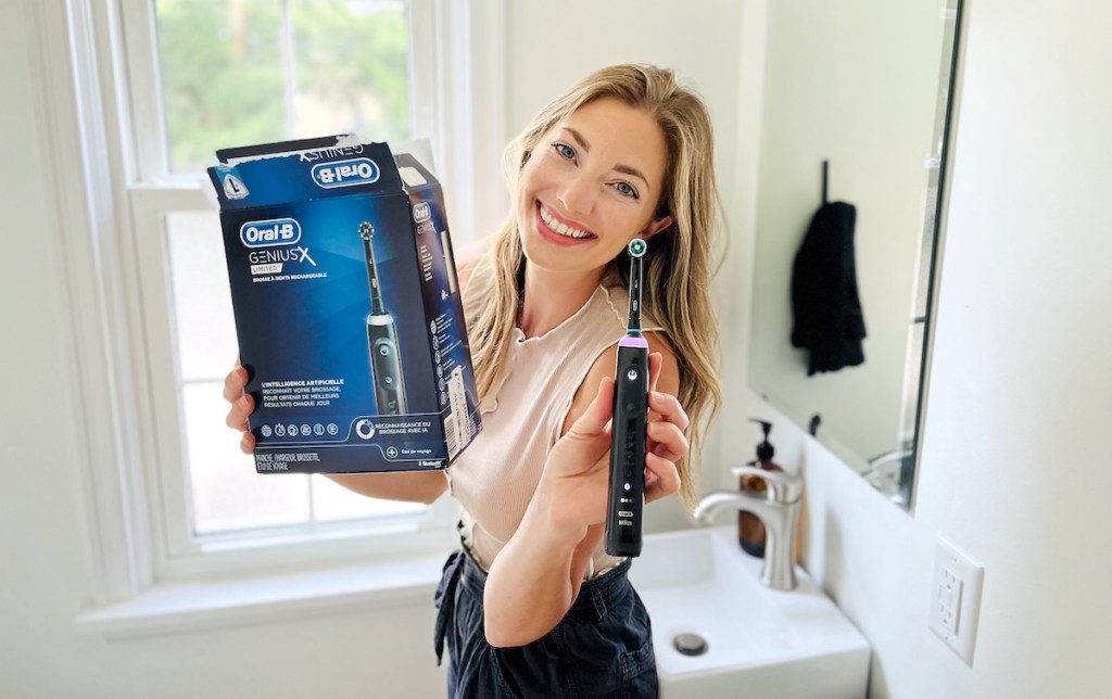 woman holding box and oral b genius x toothbrush in bathroom
