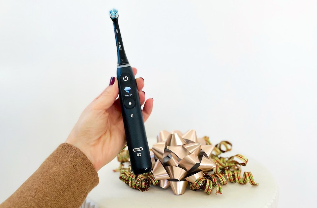 hand holding black oral b toothbrush with holiday bows