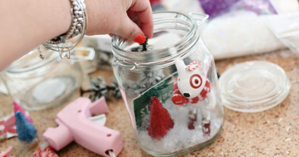 placing ornaments inside mason jar snow globe