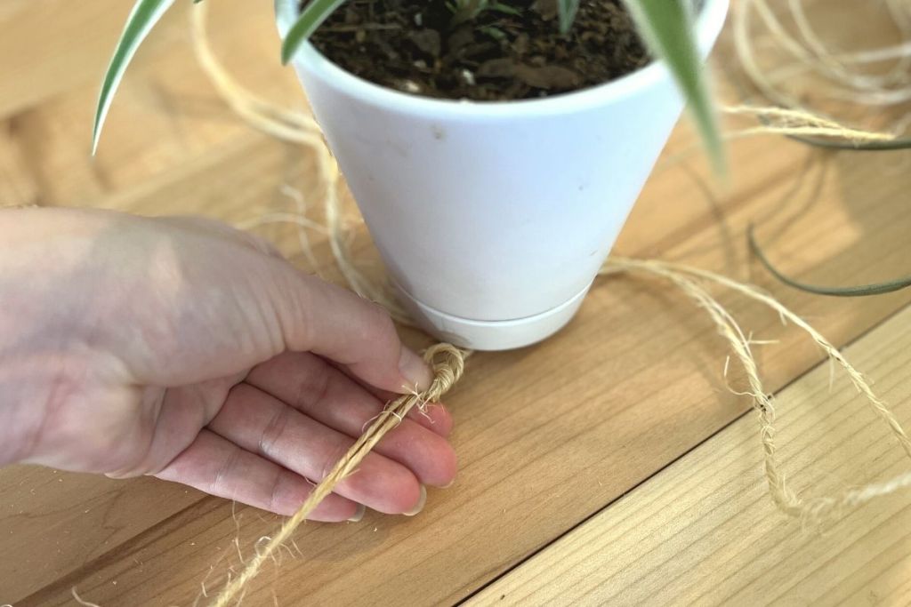 tying a knot at the base of a DIY macrame plant holder