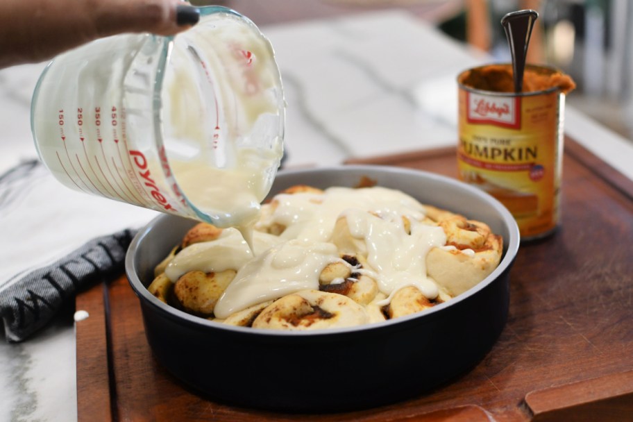 pouring cream cheese glaze over pumpkin cinnamon rolls