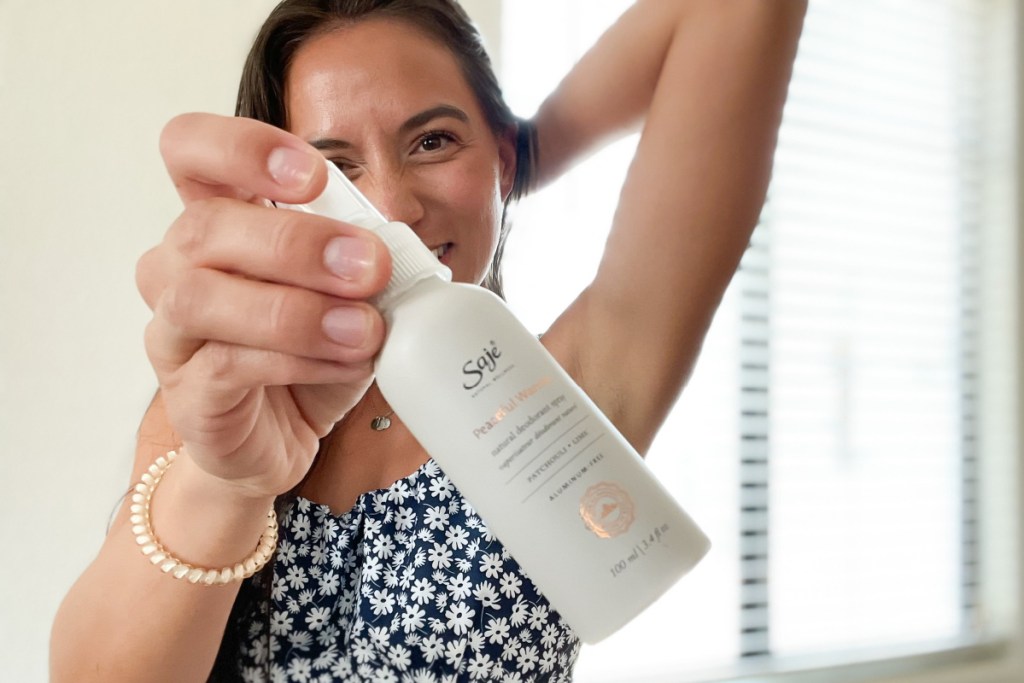 woman applying deodorant spray under arm