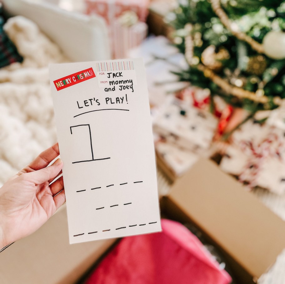 hand holding hangman game in front of christmas tree