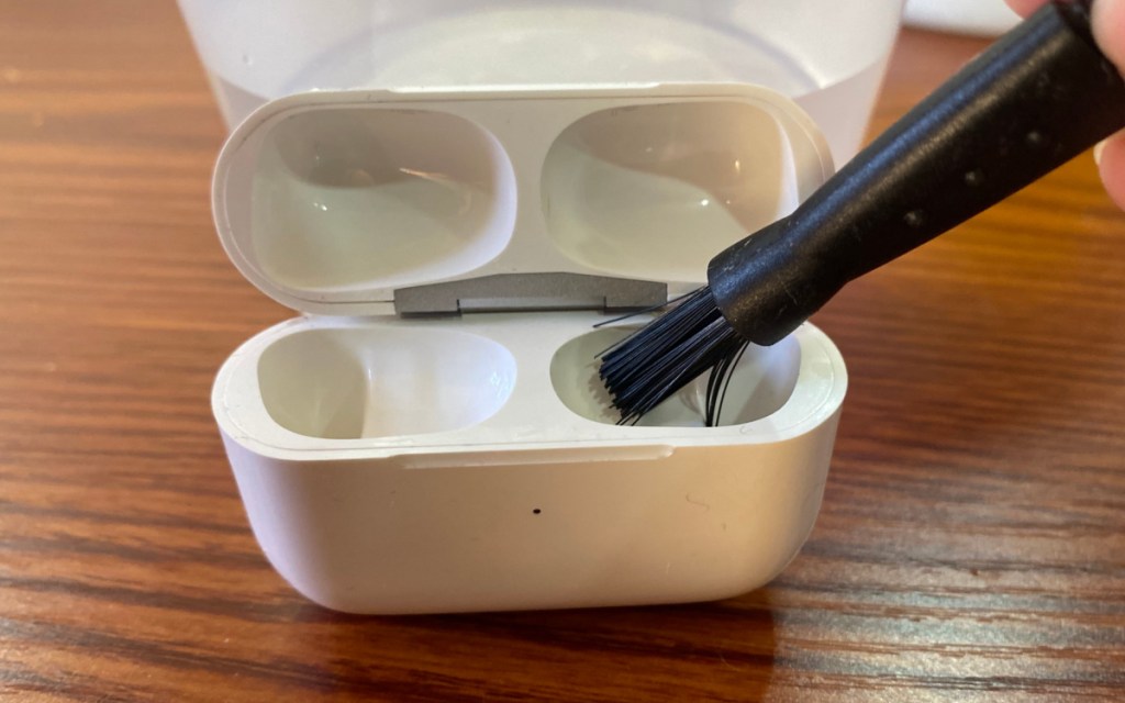 using small bristle brush to clean airpods