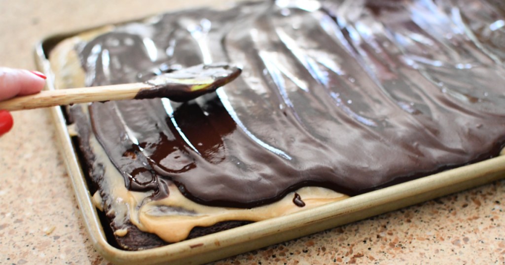 spreading chocolate glaze over a cake
