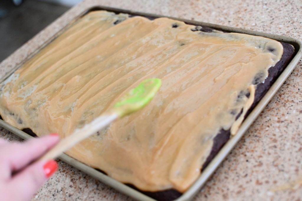 spreading peanut butter glaze on texas sheet cake