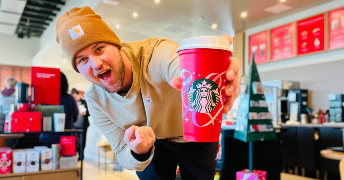 man holding a red plastic cup with holiday decorations on it