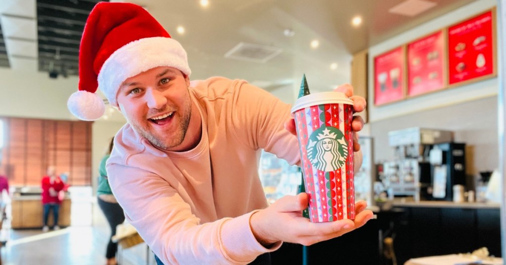 man holding a starbucks holiday cup