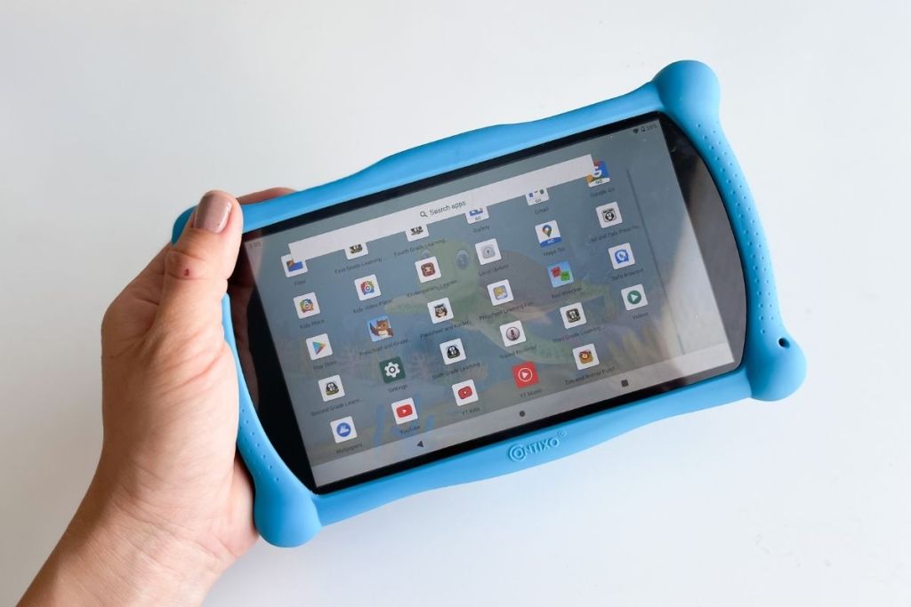 holding a Contixo tablet with home screen and apps