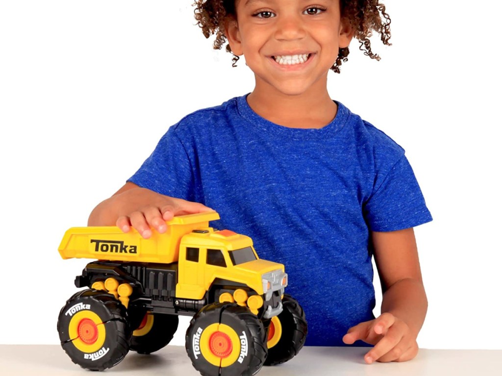 boy playing with a yellow toy monster truck