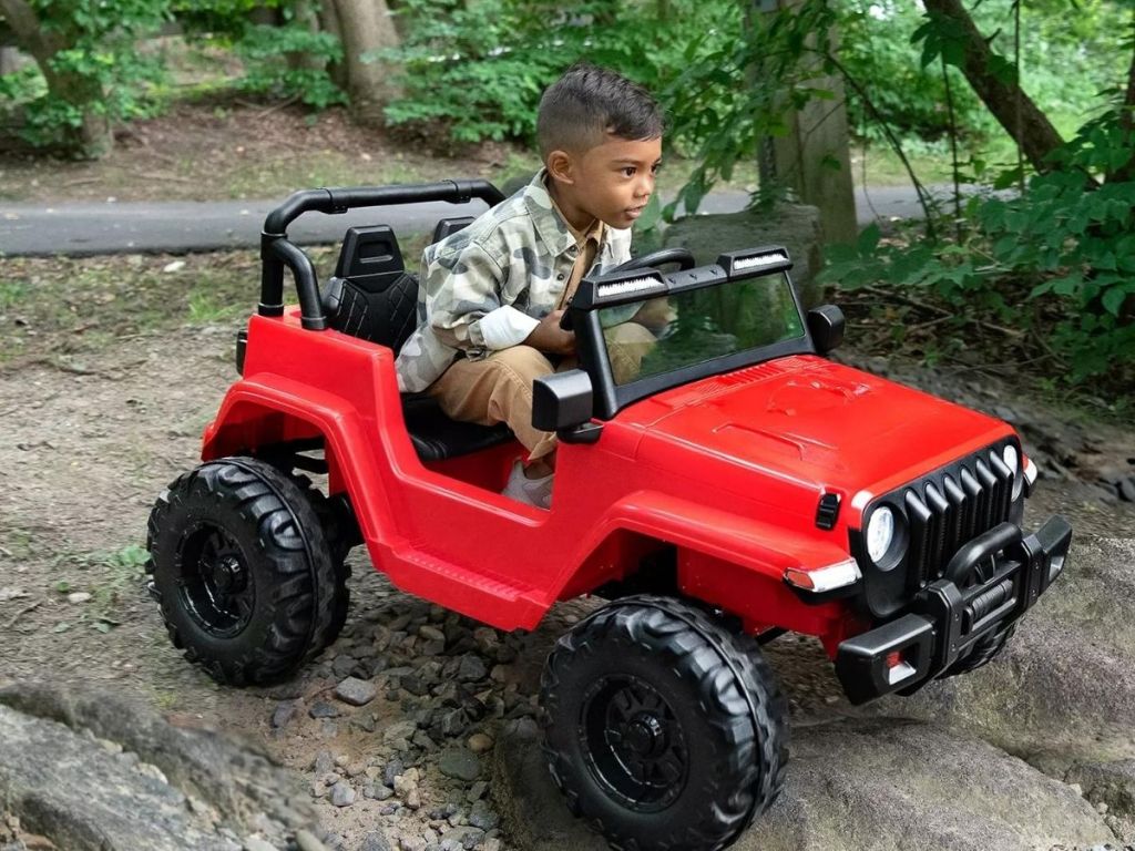 kid driving red toy jeep