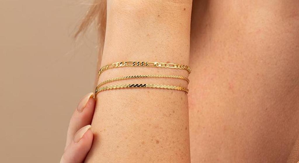 close up of arm wearing three gold bracelets