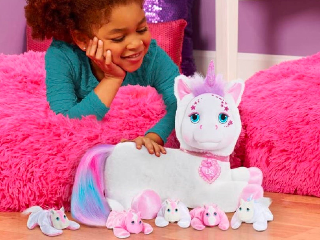 girl laying on pink beanbag chair playing with surprise unicorn toy