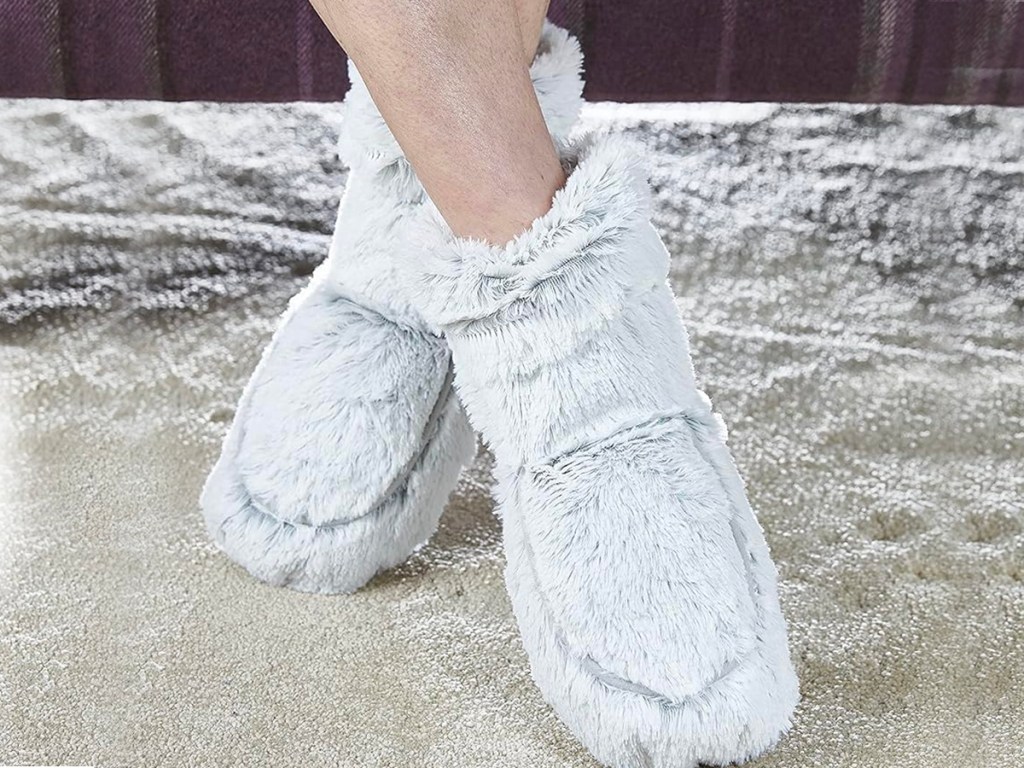 person wearing gray warmies boots on carpet