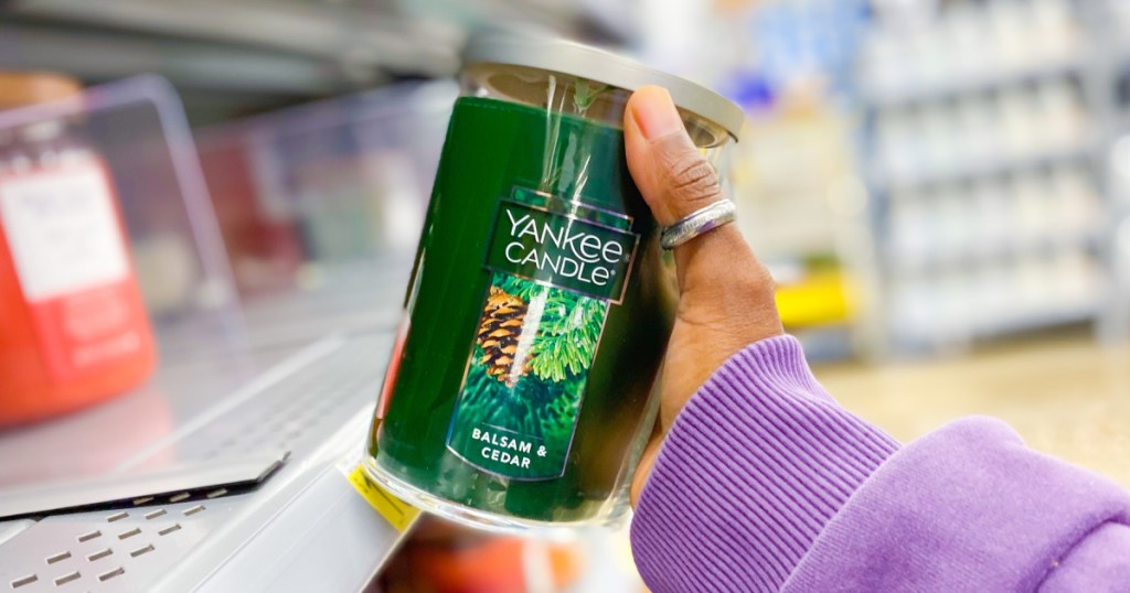 hand pulling a green yankee candle off a store shelf