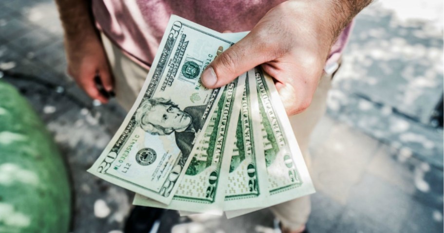 man holding $20 cash bills