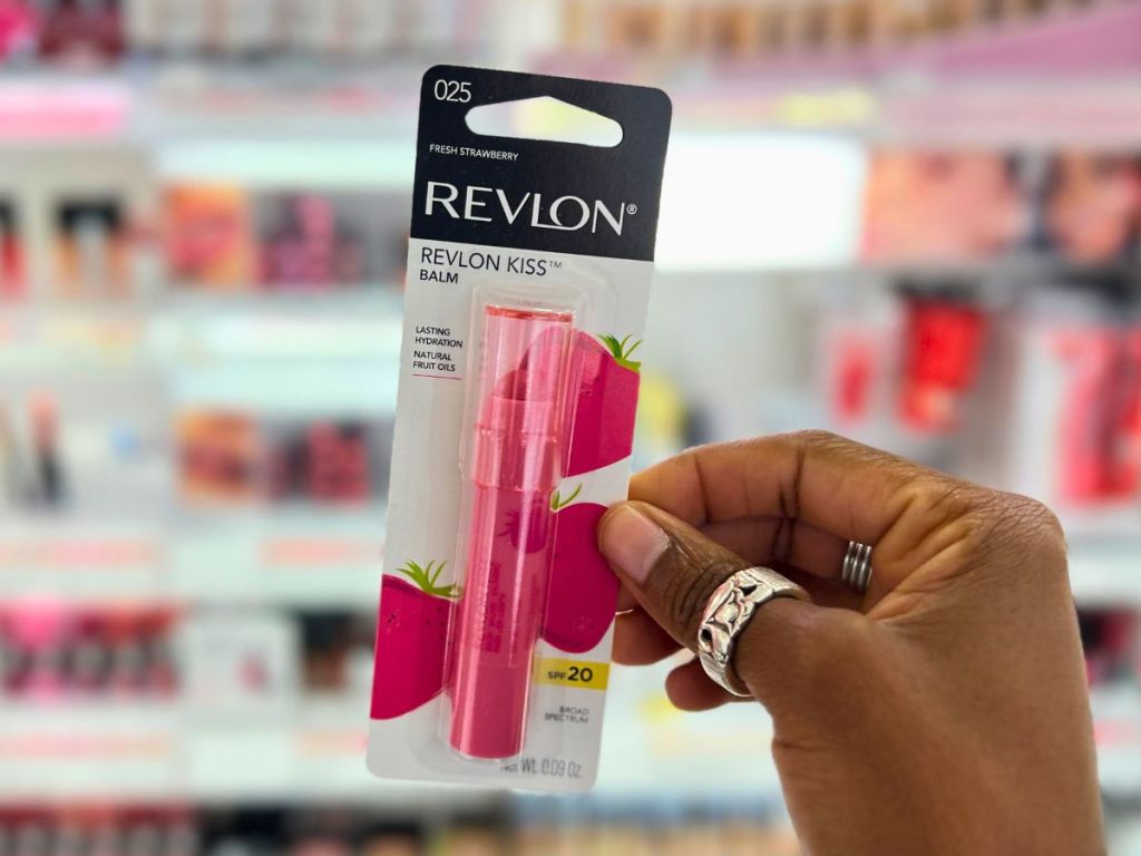 hand holding a Revlon Kiss Lip Balm in cosmetic aisle of store