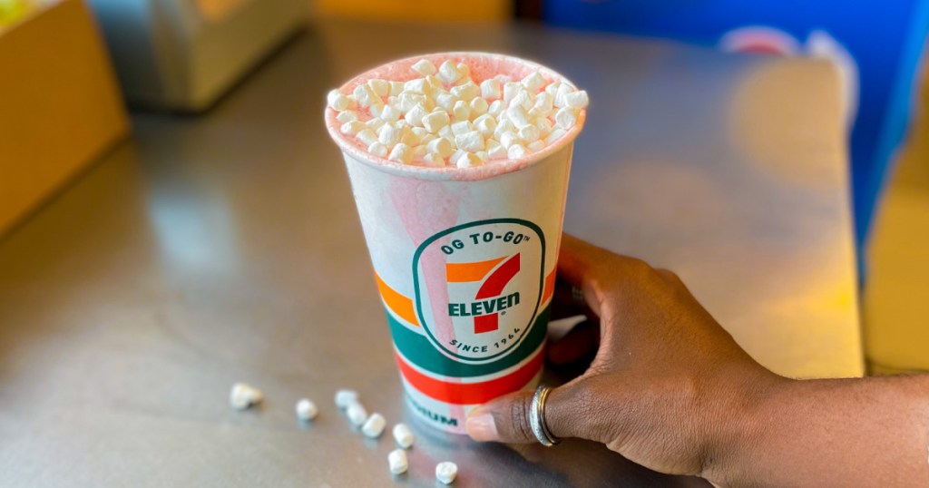 person holding cup of 7-eleven pink colored hot chocolate
