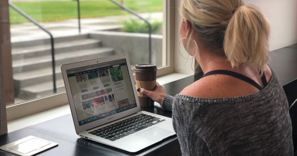 woman looking at a laptop holding coffee