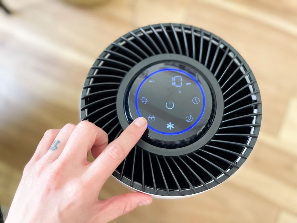 hand pushing buttons on an air purifier