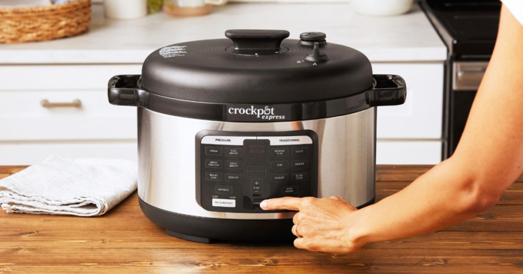 pushing button on Crock-Pot Express Oval Pressure Cooker
