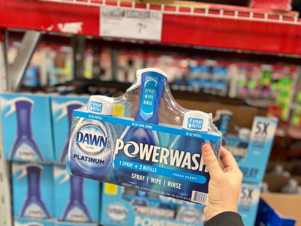 holding up set of dawn powerwash in front of display at the store 