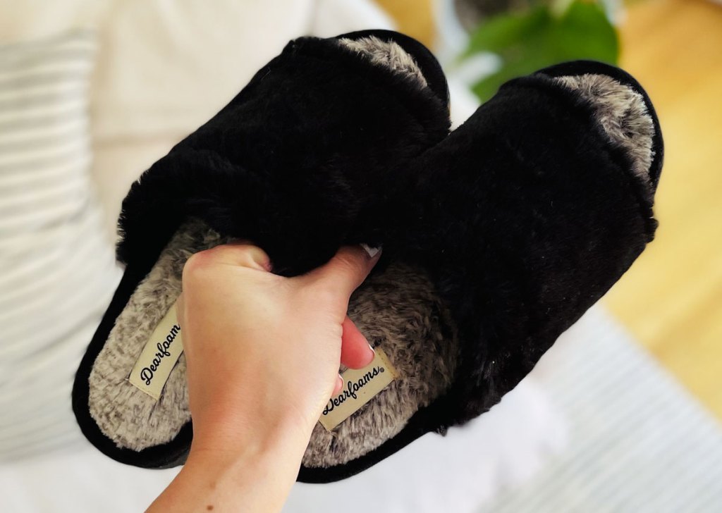 holding pair of black slippers