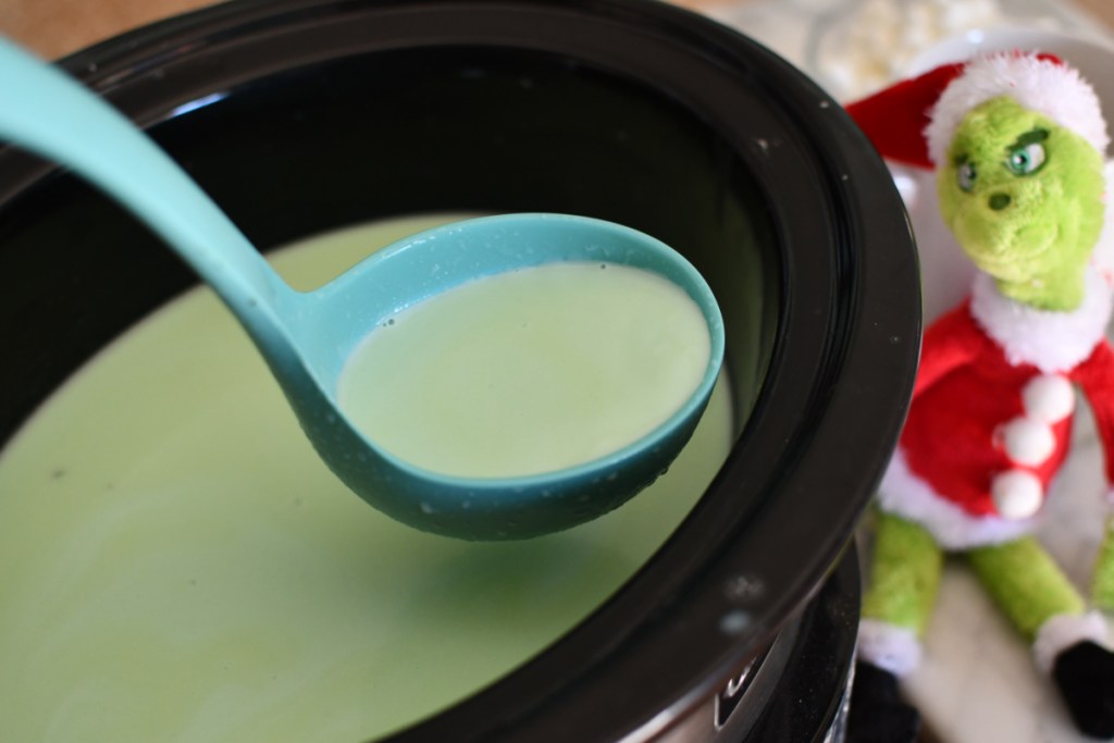 a ladle with Grinch Hot chocolate in the slow cooker