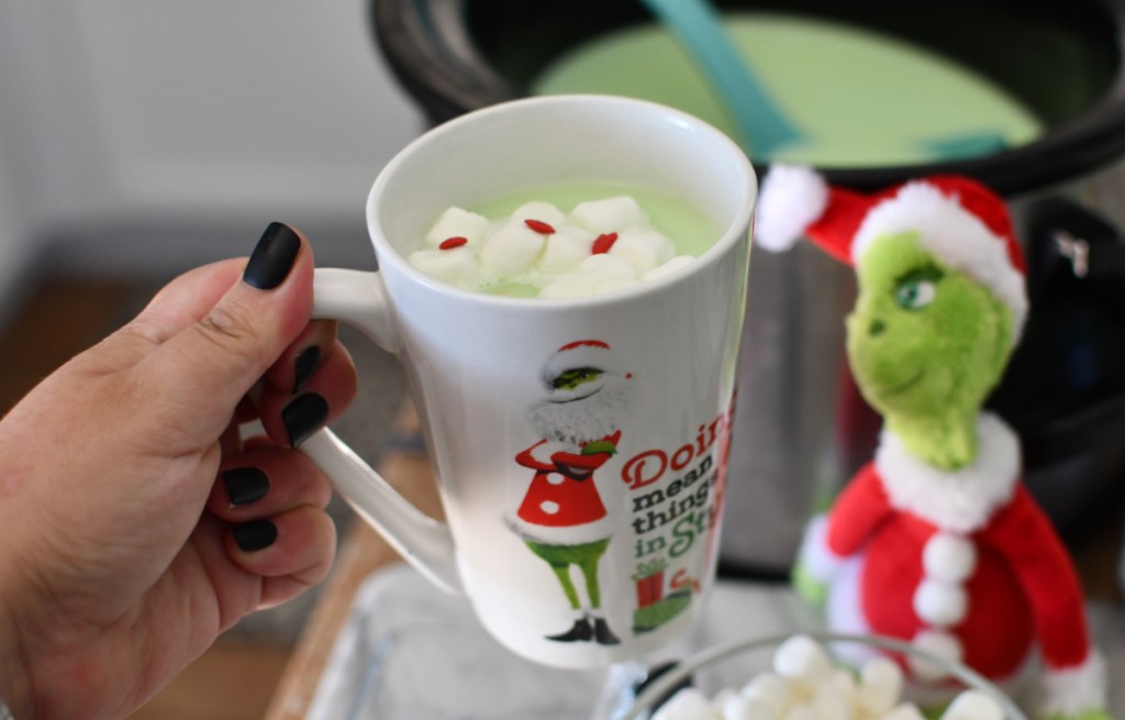 Hand holding a cup of Grinch hot chocolate