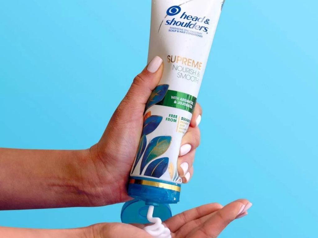Hand squeezing a Head & Shoulders supreme conditioner bottle